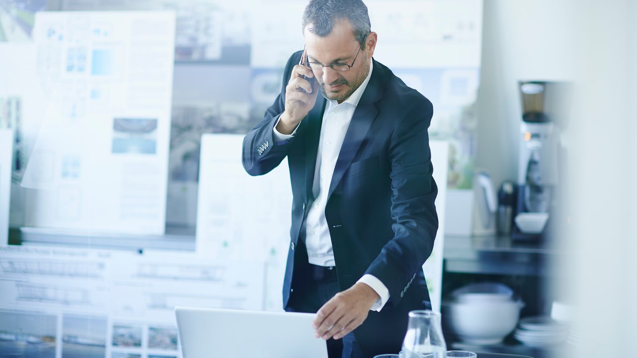 Man in office on phone with laptop